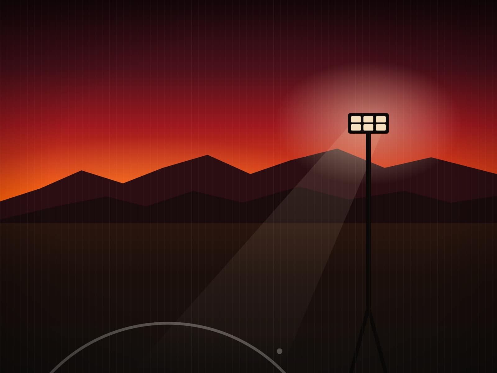 Northern Range silhouette under a flame dusk sky with a floodlight mast and chalk centre circle